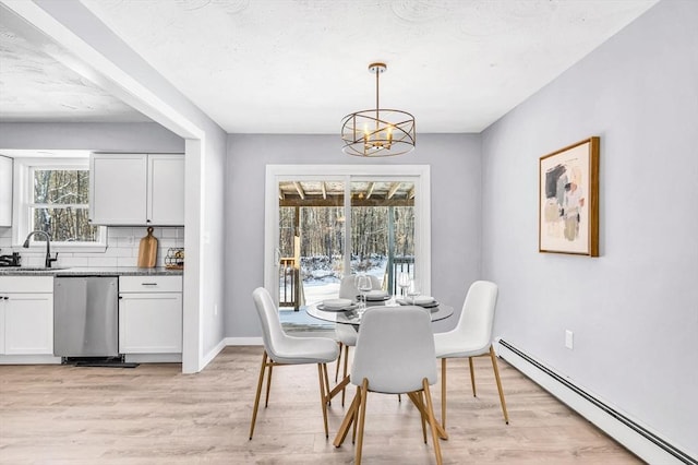 dining space with plenty of natural light, light wood-type flooring, baseboard heating, and an inviting chandelier