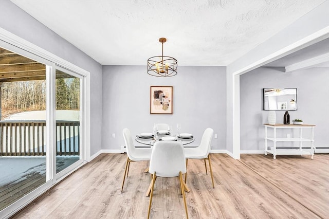 dining room featuring an inviting chandelier, a baseboard heating unit, and light hardwood / wood-style flooring