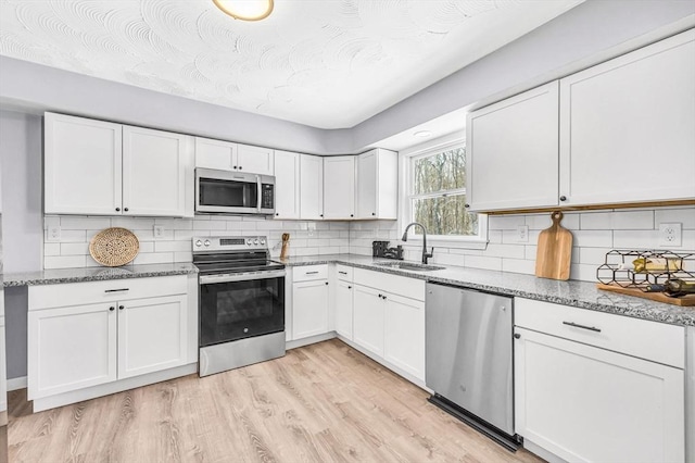 kitchen with white cabinetry, sink, stainless steel appliances, and light wood-type flooring