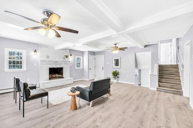 living room with beam ceiling, a brick fireplace, ceiling fan, and light wood-type flooring