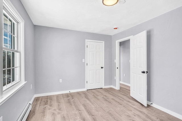 unfurnished bedroom featuring light hardwood / wood-style floors and baseboard heating