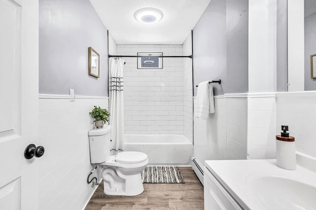 full bathroom with vanity, a baseboard heating unit, shower / bath combo with shower curtain, tile walls, and wood-type flooring