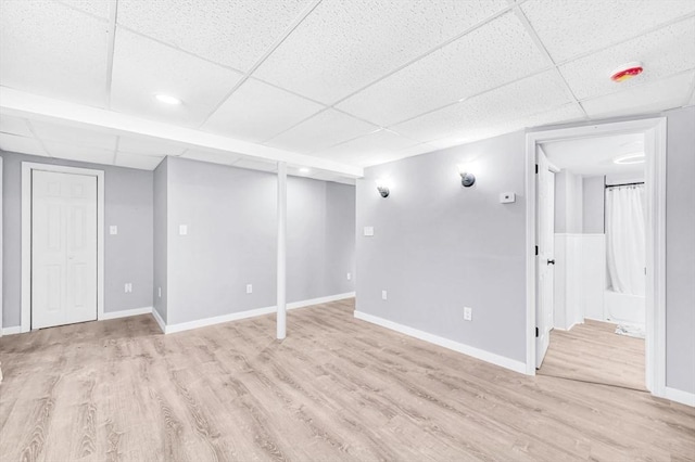 basement with light hardwood / wood-style flooring and a drop ceiling