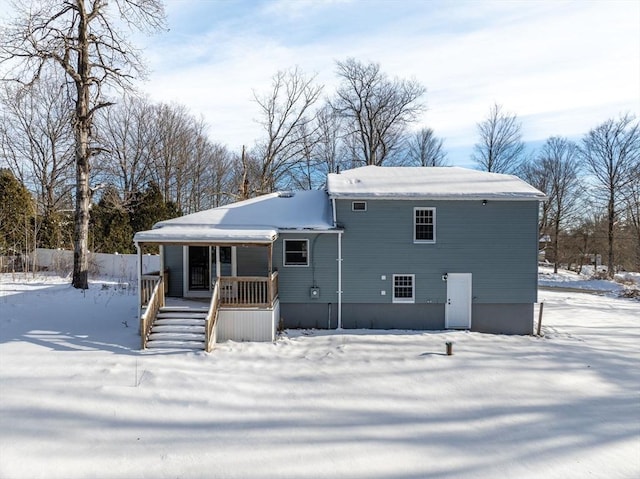 snow covered back of property with covered porch