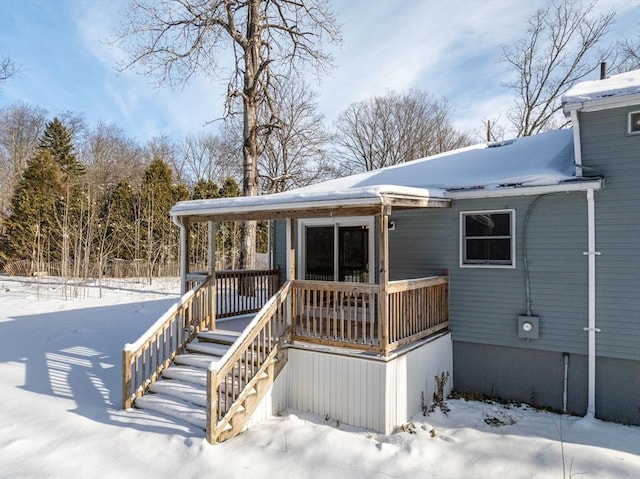 snow covered back of property with a porch