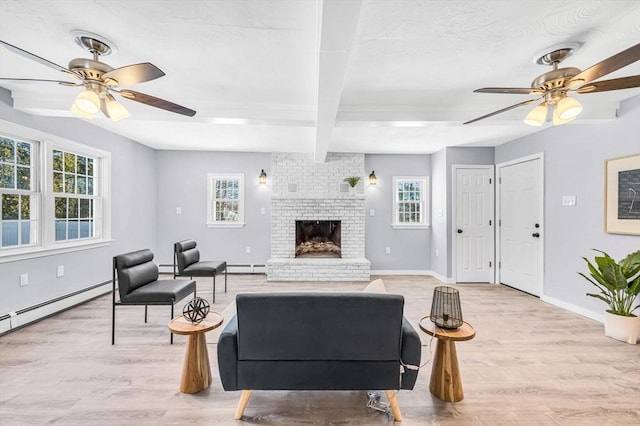 living room with light hardwood / wood-style floors, a fireplace, a wealth of natural light, and a baseboard heating unit