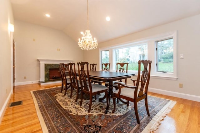 dining space with light wood finished floors, a chandelier, plenty of natural light, baseboards, and lofted ceiling