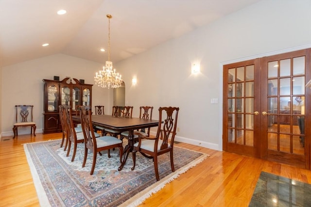 dining room featuring french doors, a chandelier, light wood-style flooring, lofted ceiling, and baseboards