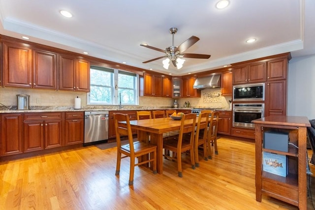 kitchen featuring stainless steel appliances, wall chimney range hood, recessed lighting, ceiling fan, and light wood-style flooring