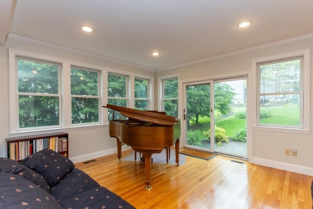 sitting room with baseboards, plenty of natural light, wood finished floors, crown molding, and recessed lighting