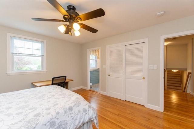 bedroom featuring light wood-type flooring, a closet, baseboards, and a ceiling fan