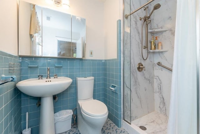 bathroom featuring a stall shower, tile walls, toilet, and a wainscoted wall
