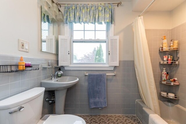 full bathroom featuring tile walls, toilet, shower / bath combination with curtain, and a wainscoted wall