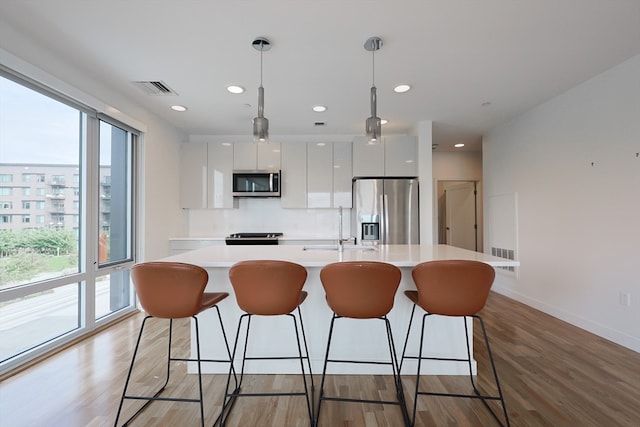 kitchen with pendant lighting, sink, white cabinetry, light hardwood / wood-style flooring, and appliances with stainless steel finishes