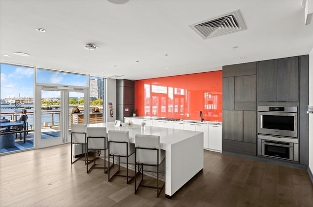 kitchen featuring wood-type flooring, white cabinetry, a water view, and a kitchen island