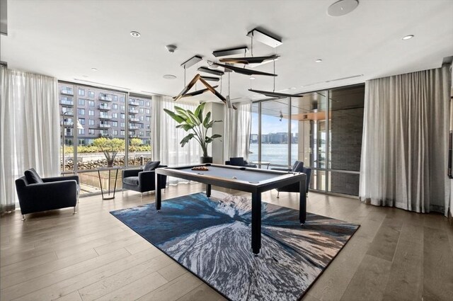 game room with a wealth of natural light, hardwood / wood-style flooring, billiards, and expansive windows