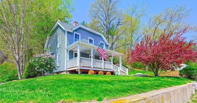 view of front of house with a front yard, covered porch, and a chimney