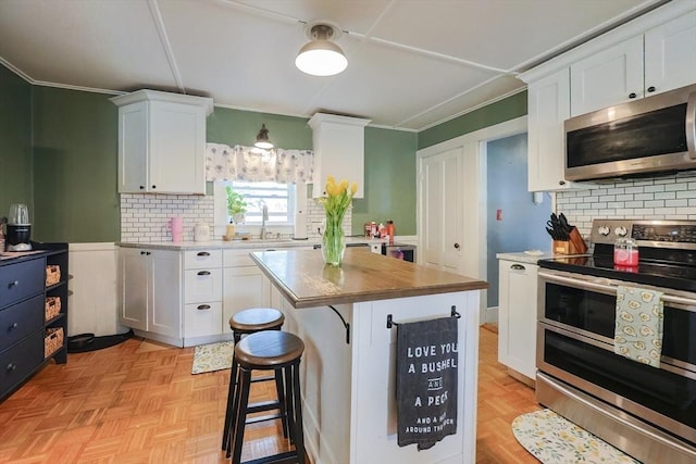kitchen featuring crown molding, white cabinetry, backsplash, and stainless steel appliances