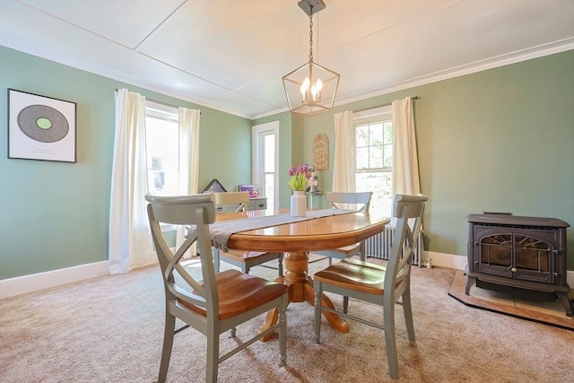 carpeted dining space with crown molding, a wood stove, baseboards, and a chandelier