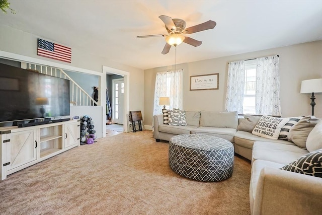 carpeted living room with plenty of natural light, a ceiling fan, and stairway