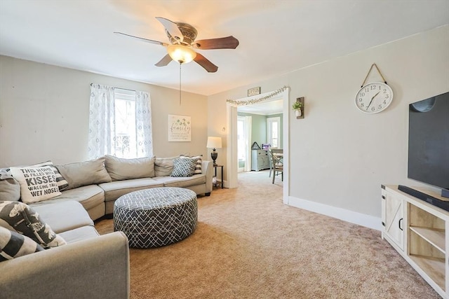 living area with ceiling fan, light colored carpet, and baseboards