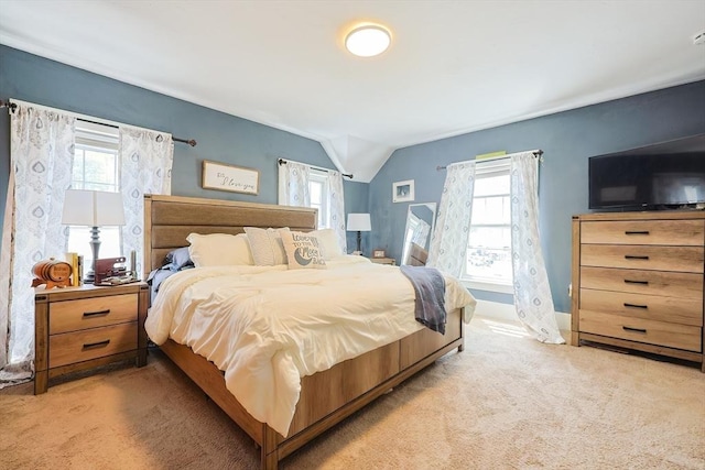 bedroom with baseboards, multiple windows, vaulted ceiling, and light colored carpet