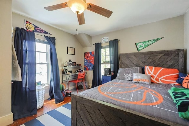 bedroom with ceiling fan, wood finished floors, and multiple windows