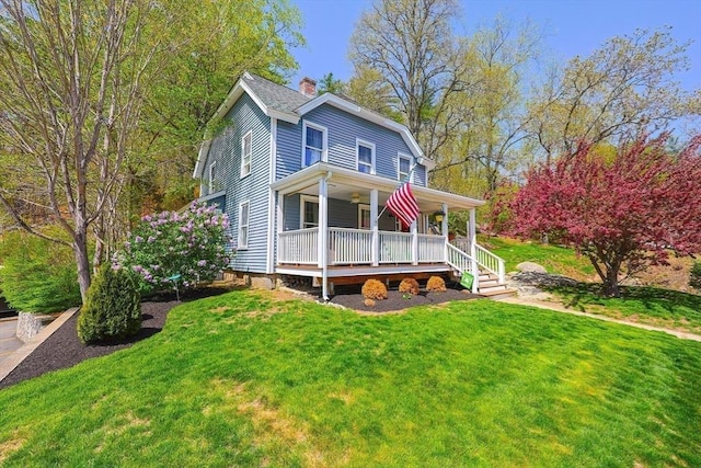 view of front of property with covered porch, a chimney, a front lawn, and ceiling fan