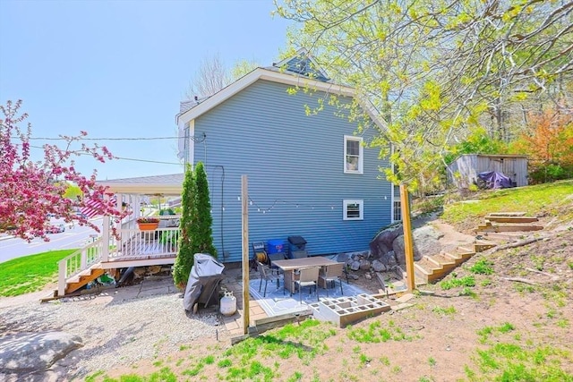 rear view of house with a storage shed, a wooden deck, stairway, an outdoor structure, and a patio