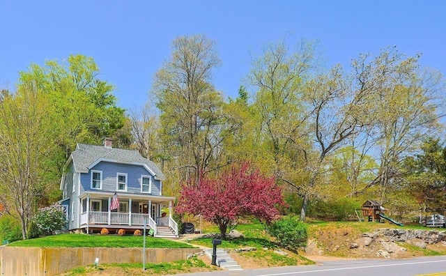 view of front facade featuring a porch, a chimney, and a playground