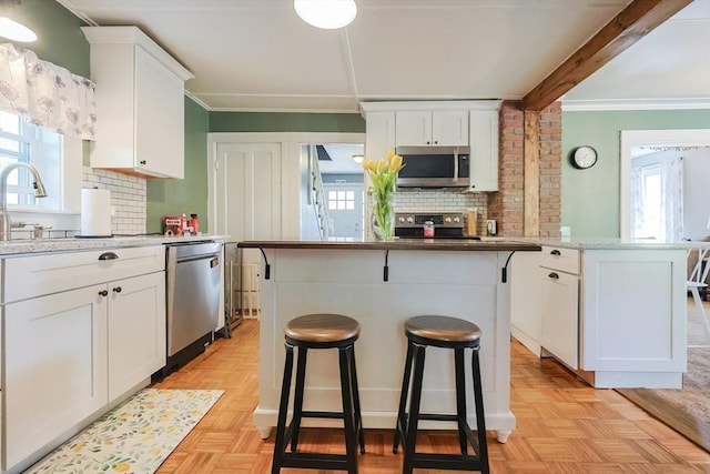 kitchen with appliances with stainless steel finishes, white cabinets, and a wealth of natural light