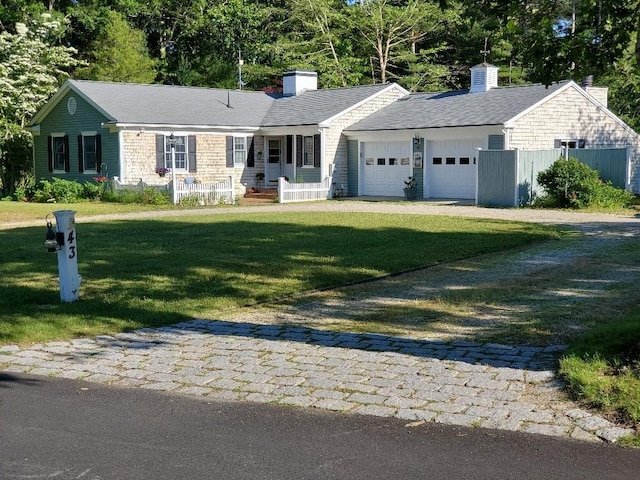 single story home with a garage, driveway, a front lawn, and a chimney