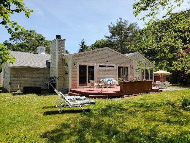 back of house featuring a deck, a lawn, and a chimney