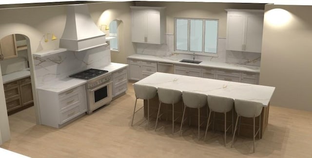 kitchen with light stone counters, gas cooktop, a sink, stainless steel dishwasher, and a kitchen bar