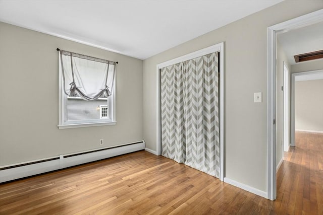 15 Dodge Hill Rd, Sutton, MA 01590 - unfurnished bedroom featuring baseboard heating, wood finished floors, baseboards, and a closet