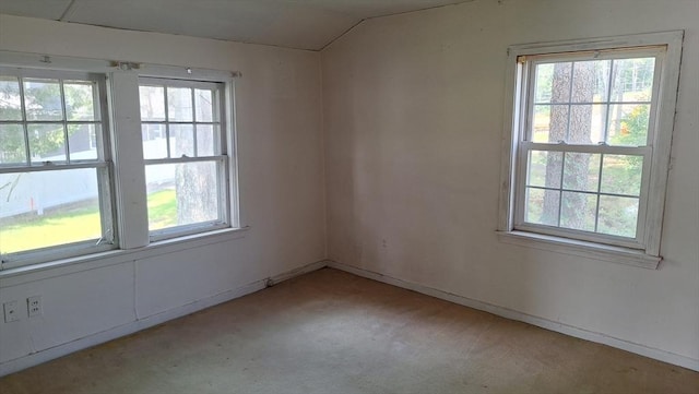 empty room with light colored carpet, lofted ceiling, and a healthy amount of sunlight