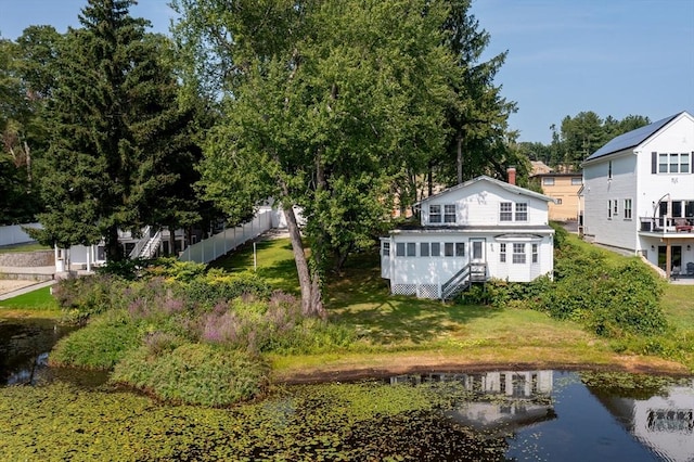 back of house featuring a water view and fence