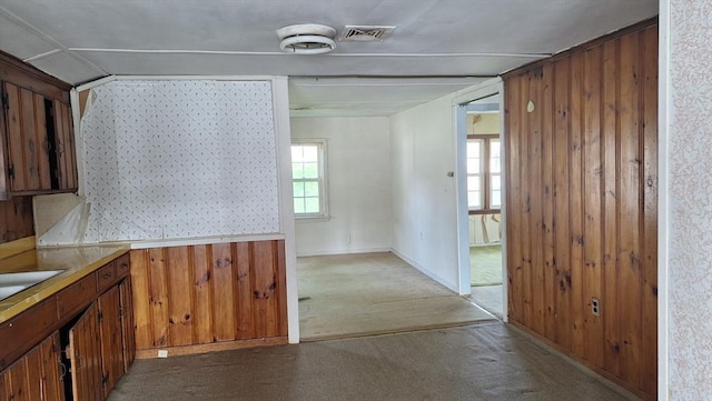 kitchen featuring wooden walls, light carpet, visible vents, light countertops, and brown cabinets