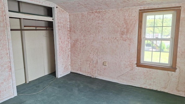 unfurnished bedroom featuring a closet, multiple windows, and dark carpet