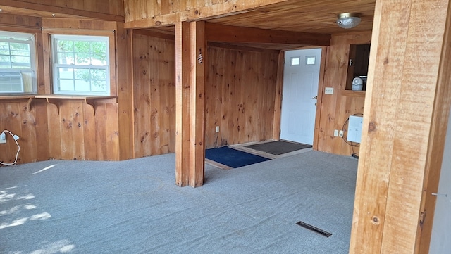 unfurnished room featuring wood walls, beamed ceiling, and carpet flooring