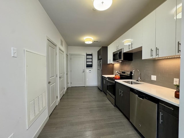 99 Tremont Unit 205, Boston, MA 02135 - kitchen featuring stainless steel appliances, light countertops, backsplash, white cabinets, and dark wood-style floors