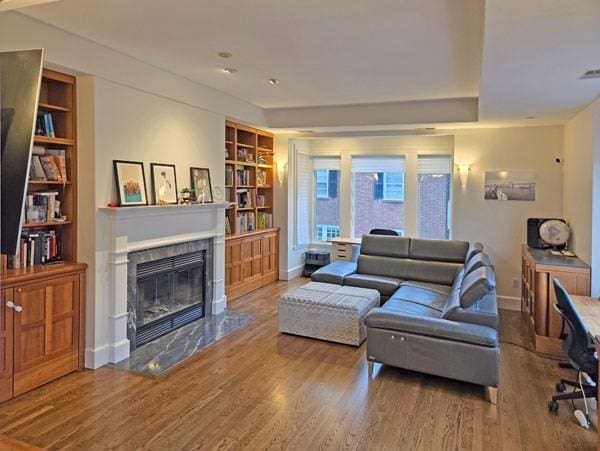 living room with baseboards, built in features, wood finished floors, and a fireplace