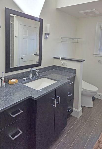 bathroom featuring toilet, wood finish floors, baseboards, and vanity