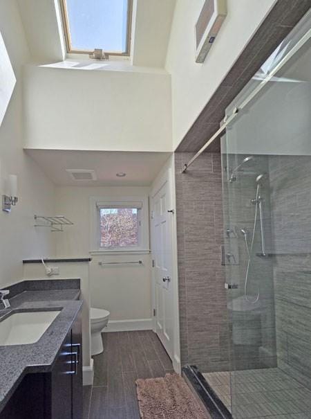 bathroom featuring wood tiled floor, toilet, a shower stall, and vanity