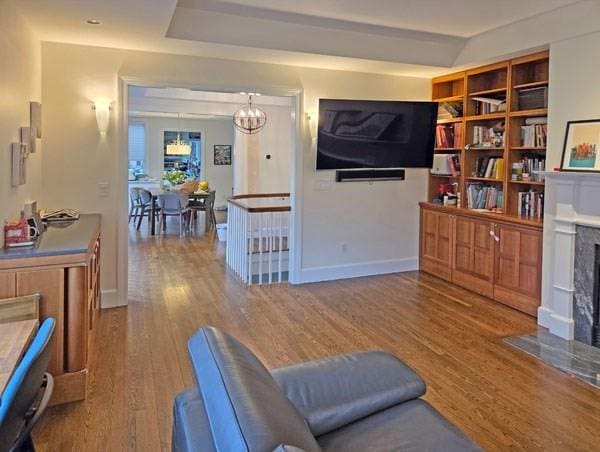living area featuring baseboards, wood finished floors, a notable chandelier, and a premium fireplace