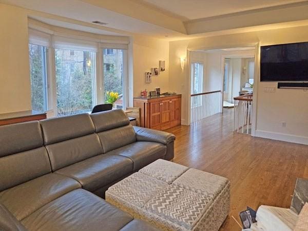 living room with baseboards, visible vents, and wood finished floors