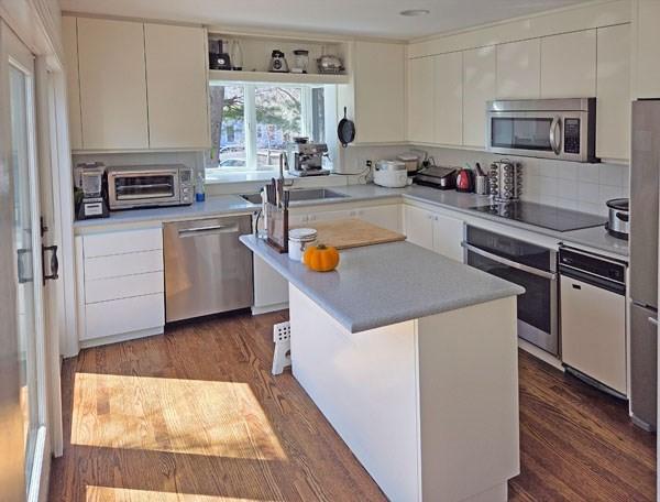 kitchen featuring white cabinets, stainless steel appliances, light countertops, and dark wood-type flooring