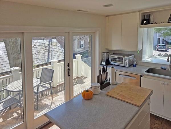 kitchen with a sink, light countertops, a center island, a toaster, and stainless steel dishwasher