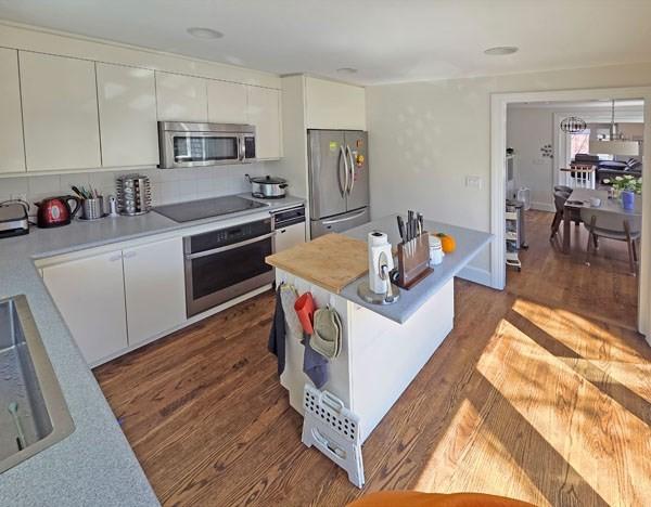 kitchen featuring dark wood-style flooring, appliances with stainless steel finishes, light countertops, a sink, and white cabinetry