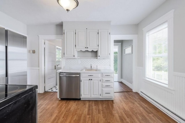 24 Tampa St, Worcester, MA 01604 - kitchen with stainless steel appliances, a baseboard heating unit, a wainscoted wall, light countertops, and light wood-type flooring